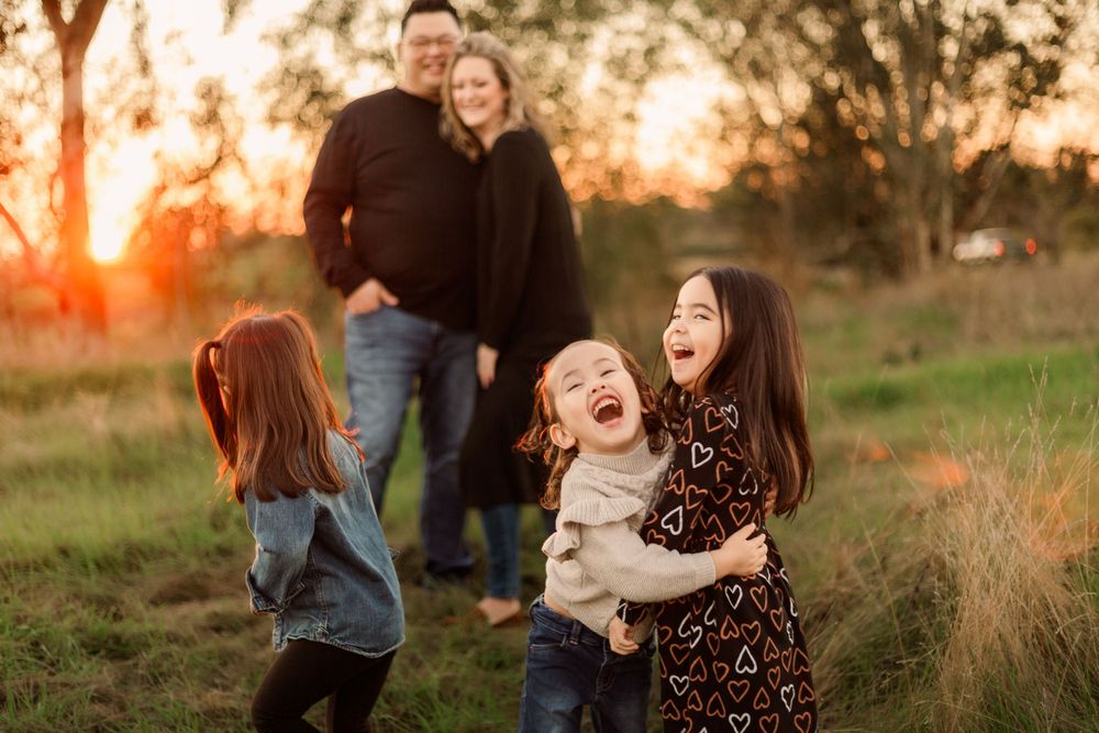 Children playing and laughing together outdoors during sunset.