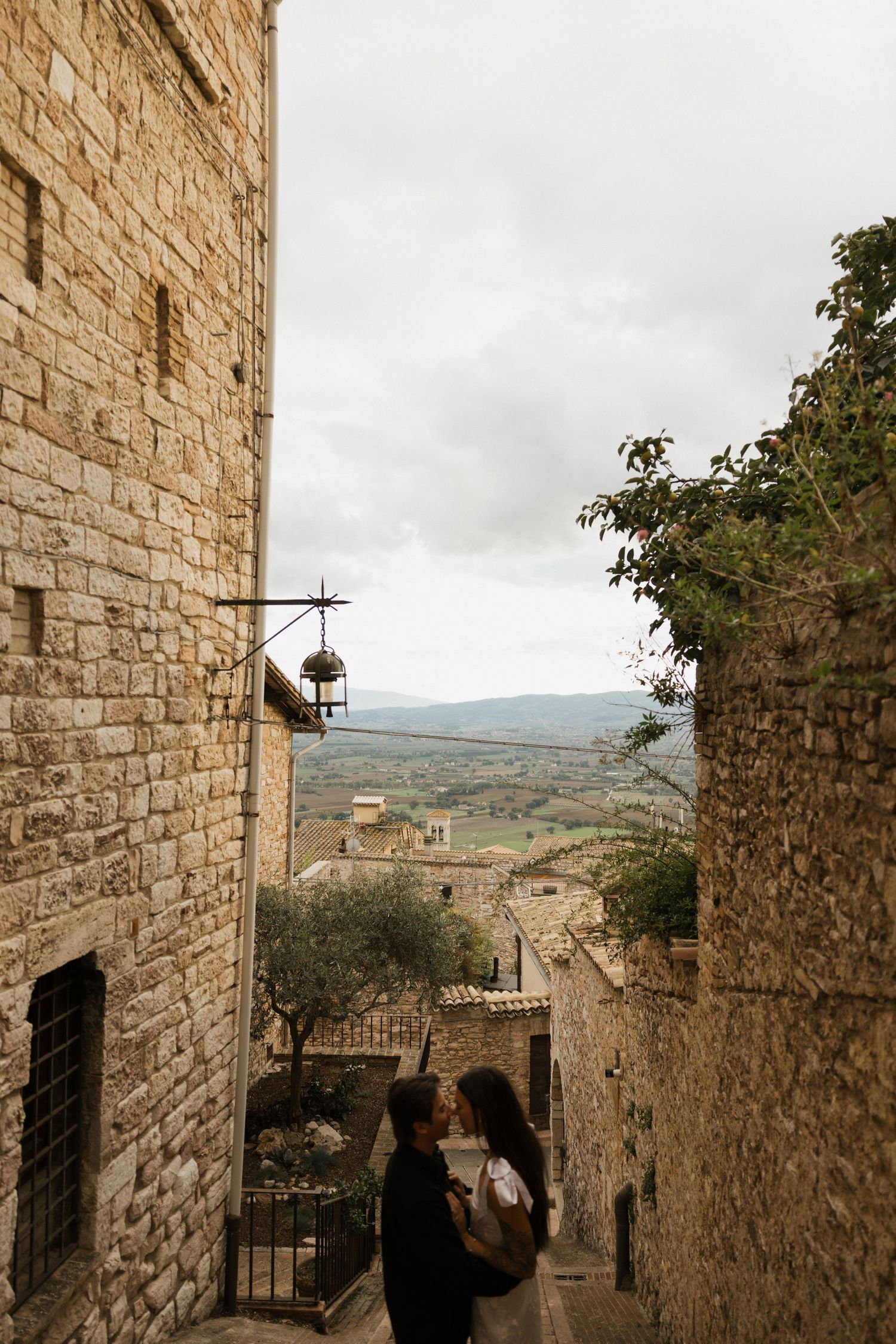 Stone alleyway with ancient buildings overlooking a scenic hillside landscape in an Italian medieval town.