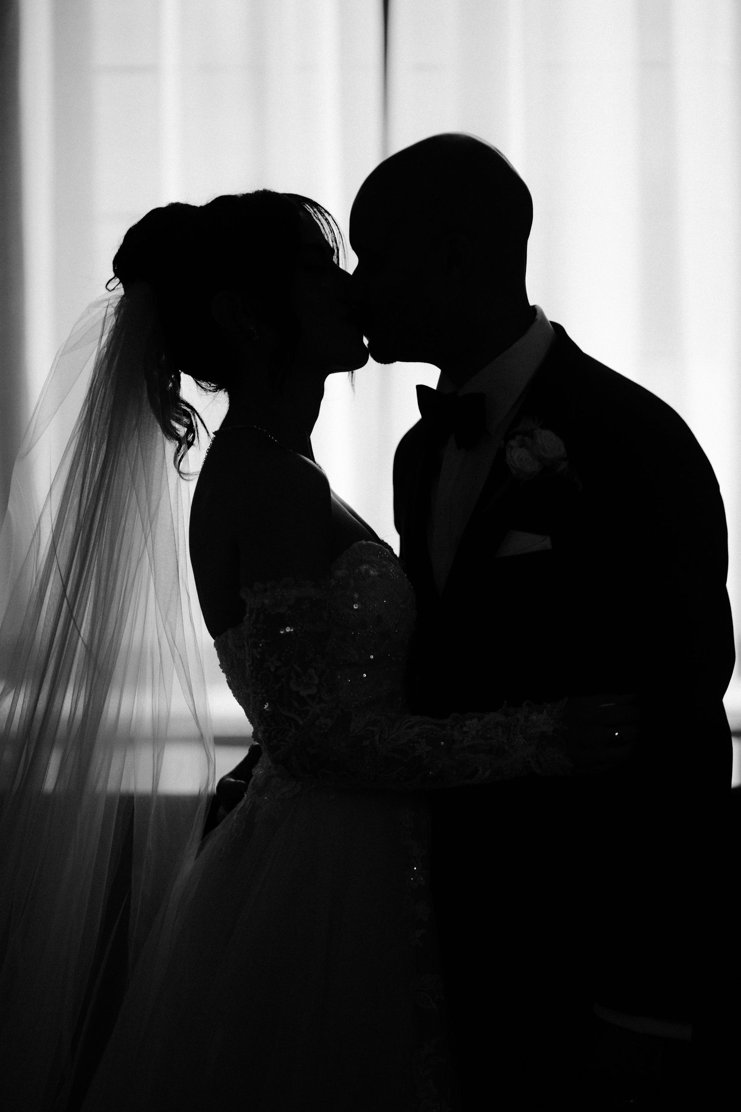 A series of silhouetted romantic wedding photos showing couples kissing in black and white.