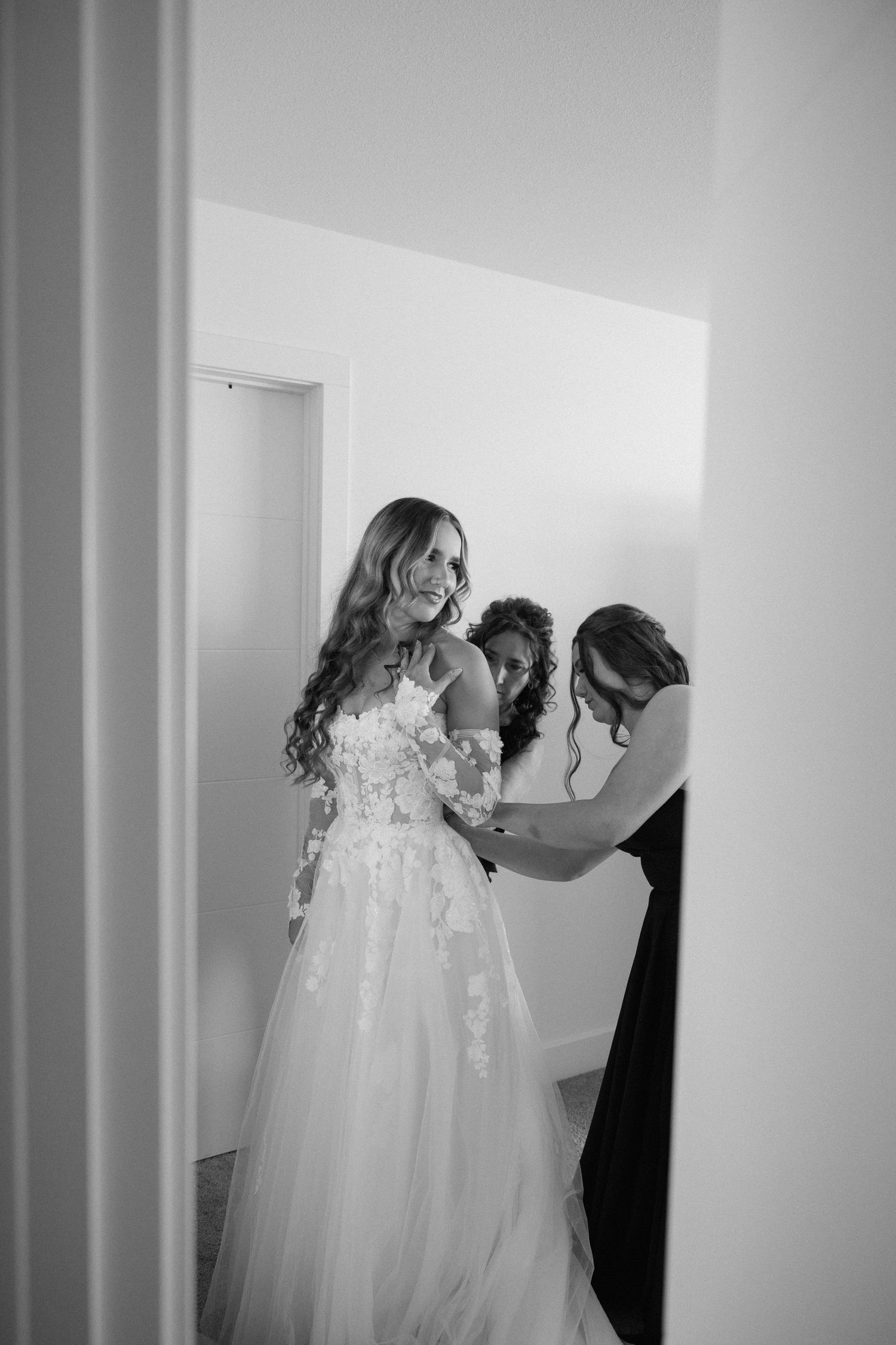 Black and white photos showing wedding dress preparations in a bright white room.