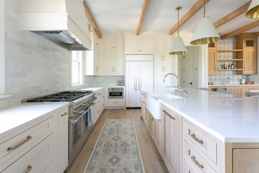Elegant white kitchen with marble countertops and brass fixtures in an open concept layout.