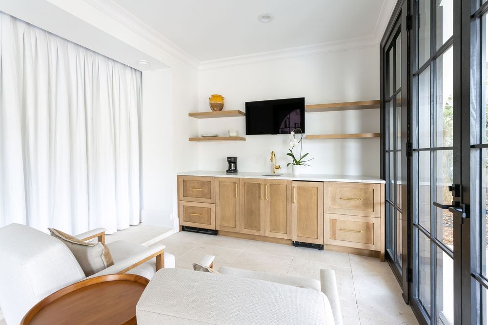 Minimalist living space with floor-to-ceiling windows, white curtains, and natural wood accents.