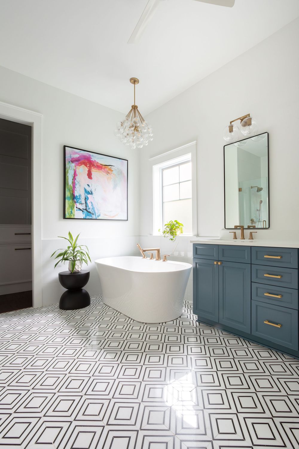 Modern bathroom with geometric floor tiles, navy blue cabinets, and a freestanding white bathtub.