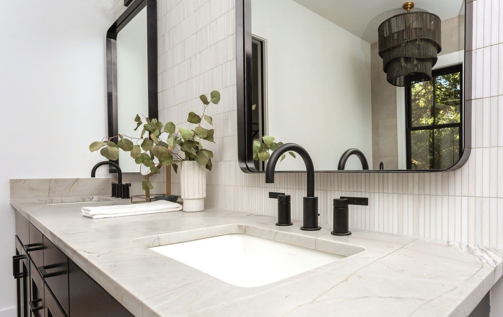 Contemporary bathroom vanity with black fixtures and white marble countertop.