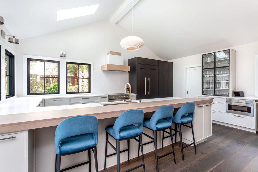 Contemporary dining area with blue bar stools and wooden counter in an open concept space.