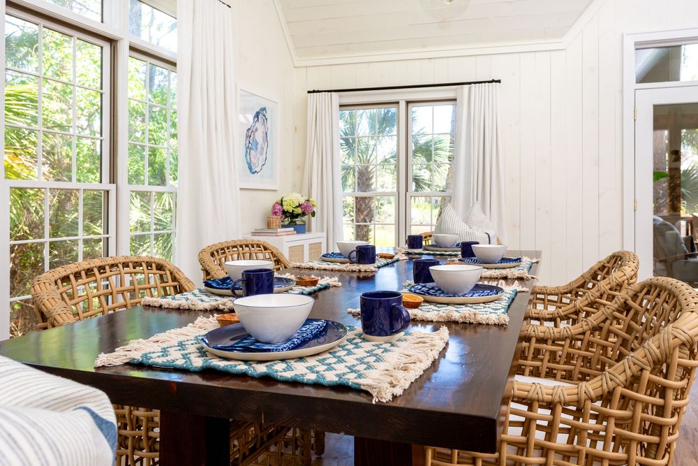 Coastal-style dining room with wicker chairs and natural light streaming through windows.