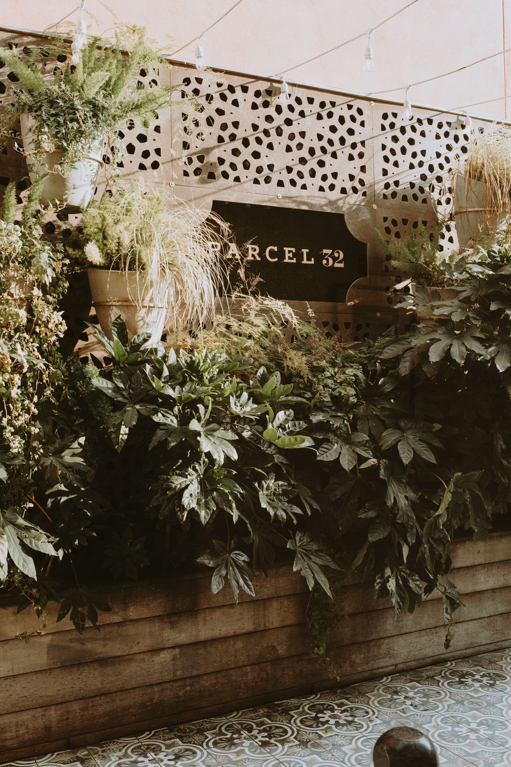 Rustic wooden planter box filled with lush greenery and white flowers against a textured wall.