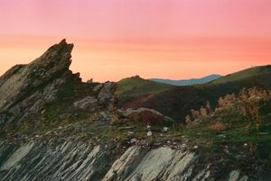 Rocky mountain ridge at sunset with layered hills and natural landscape.