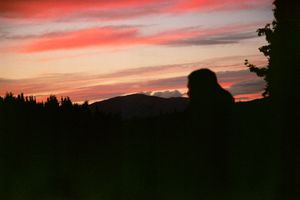 Silhouette of a person against colorful sunset sky in mountain landscape.