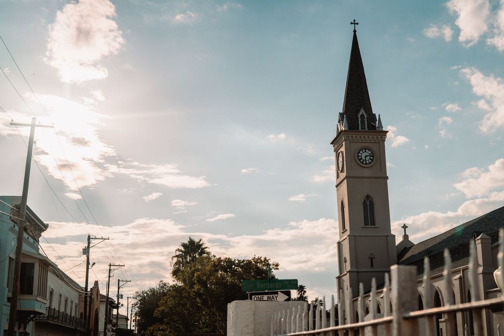 Church steeples and buildings against a bright blue sky with white clouds.