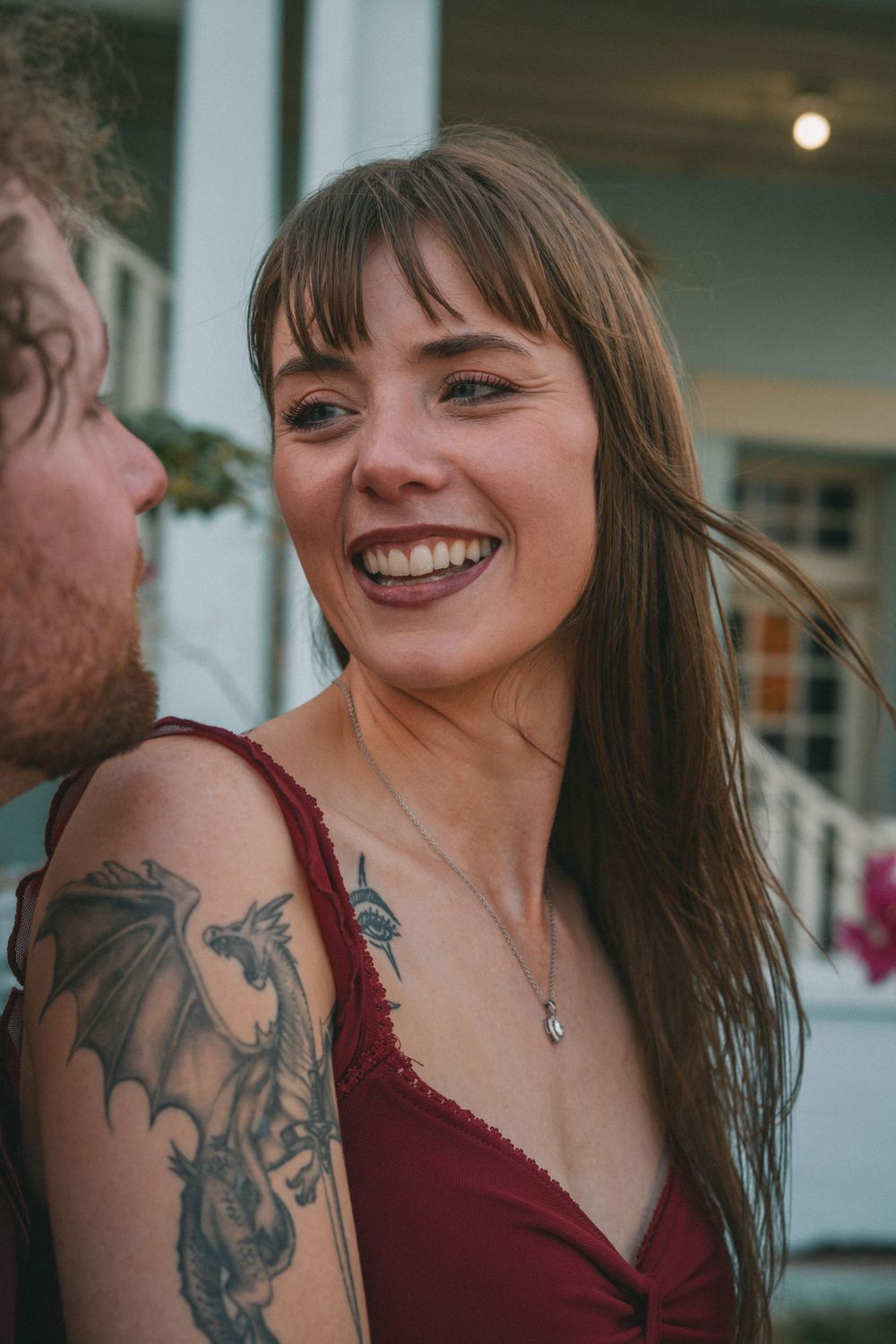 A couple shares a moment together with a dragon tattoo visible on one person's arm.