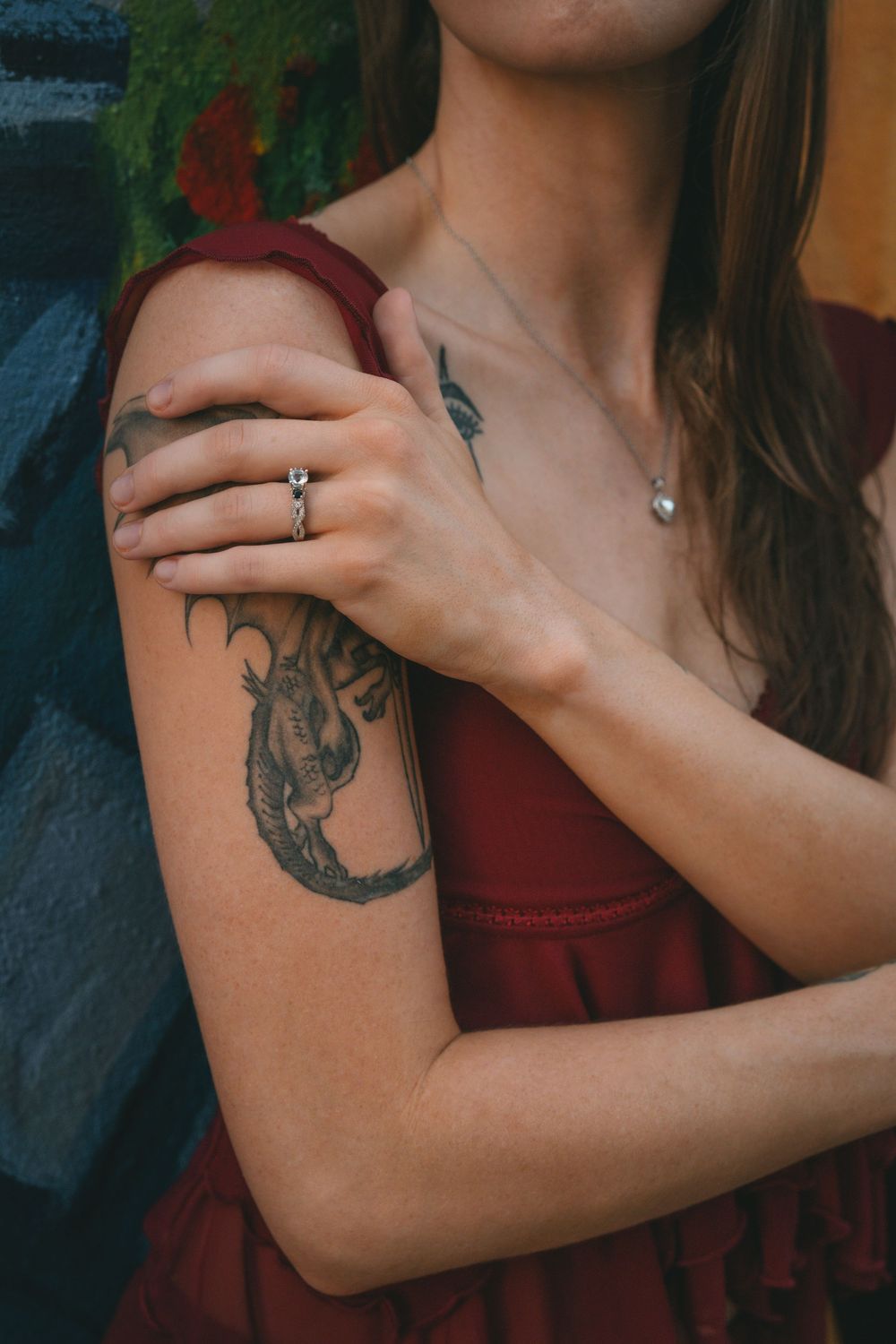 Close-up shot of a dragon tattoo on an arm with burgundy dress details.