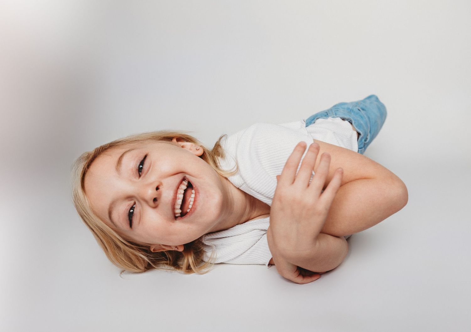 Child sitting in front of a clean white backdrop during an at-home personality portrait session in Marlton, NJ.