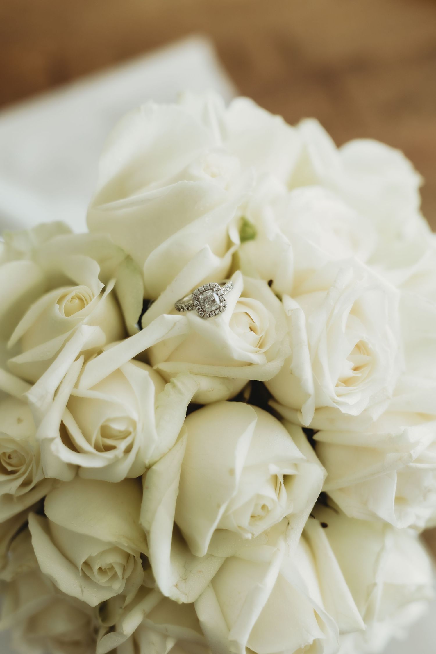 A beautiful bouquet of white roses with a diamond engagement ring nestled among the petals.
