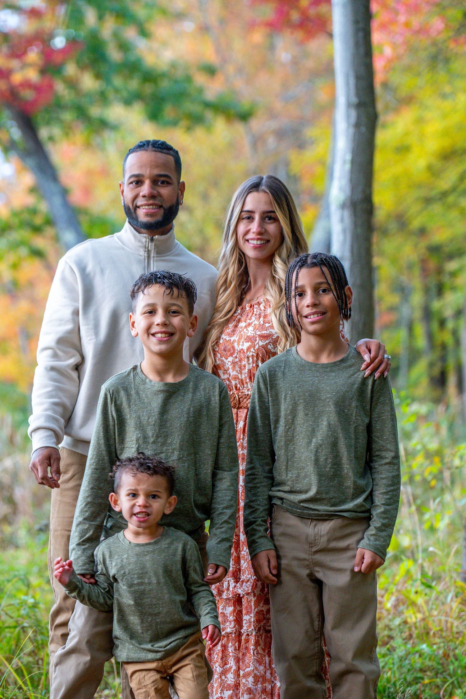 Family group photo on a porch wearing coordinated neutral tones and floral dress.