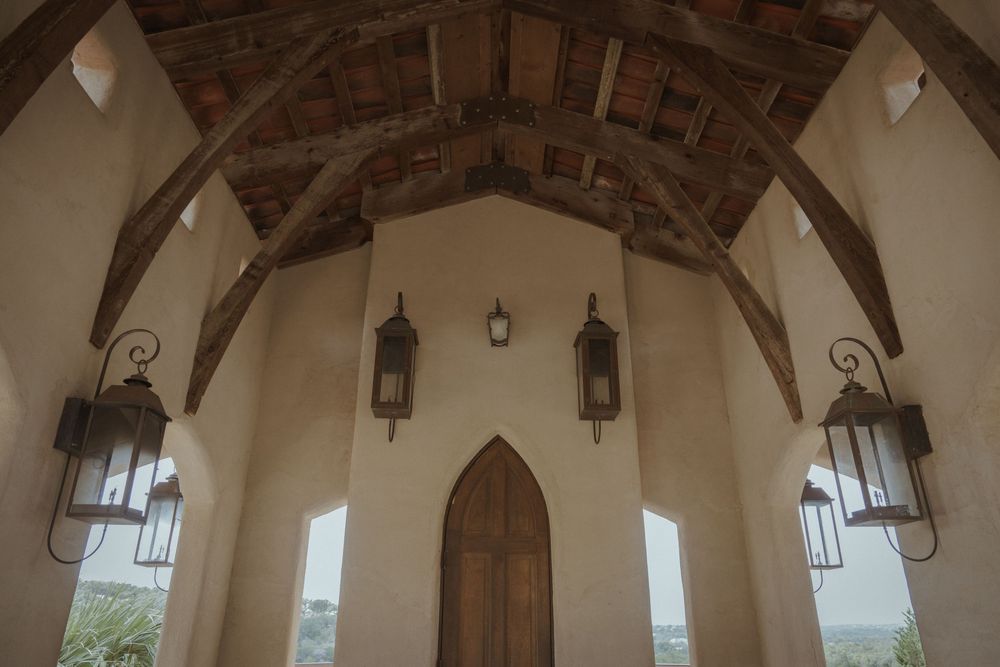 Rustic stone archway interior with hanging lanterns and white bunting decorations.