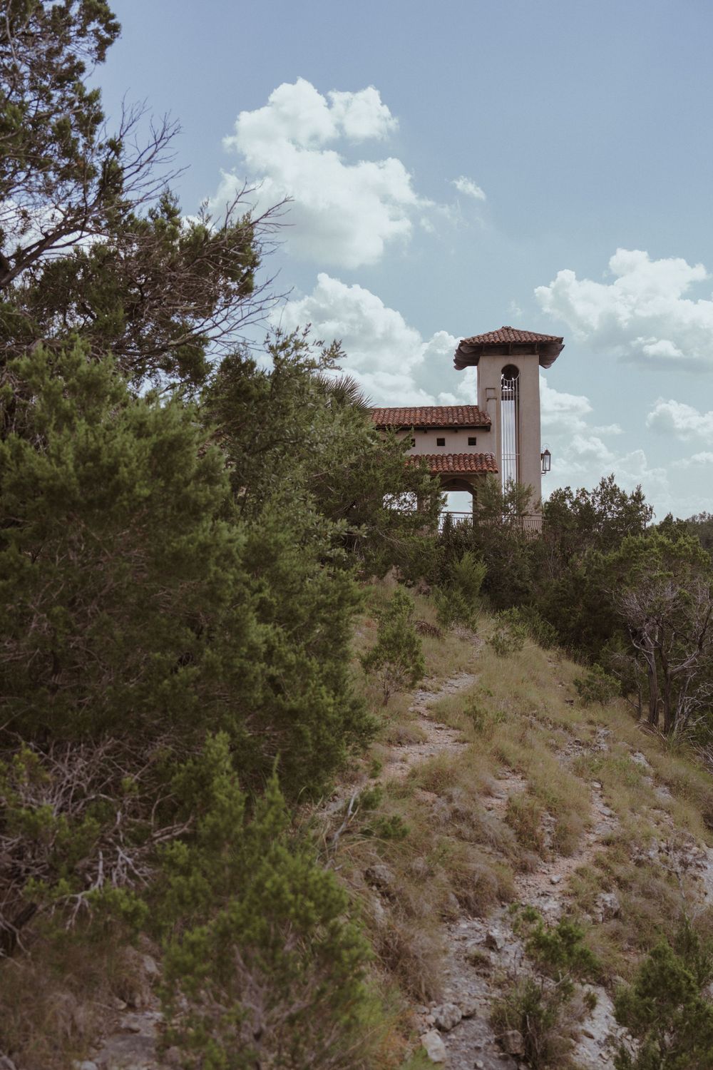 Spanish-style observation tower sits atop rocky hill surrounded by desert vegetation.