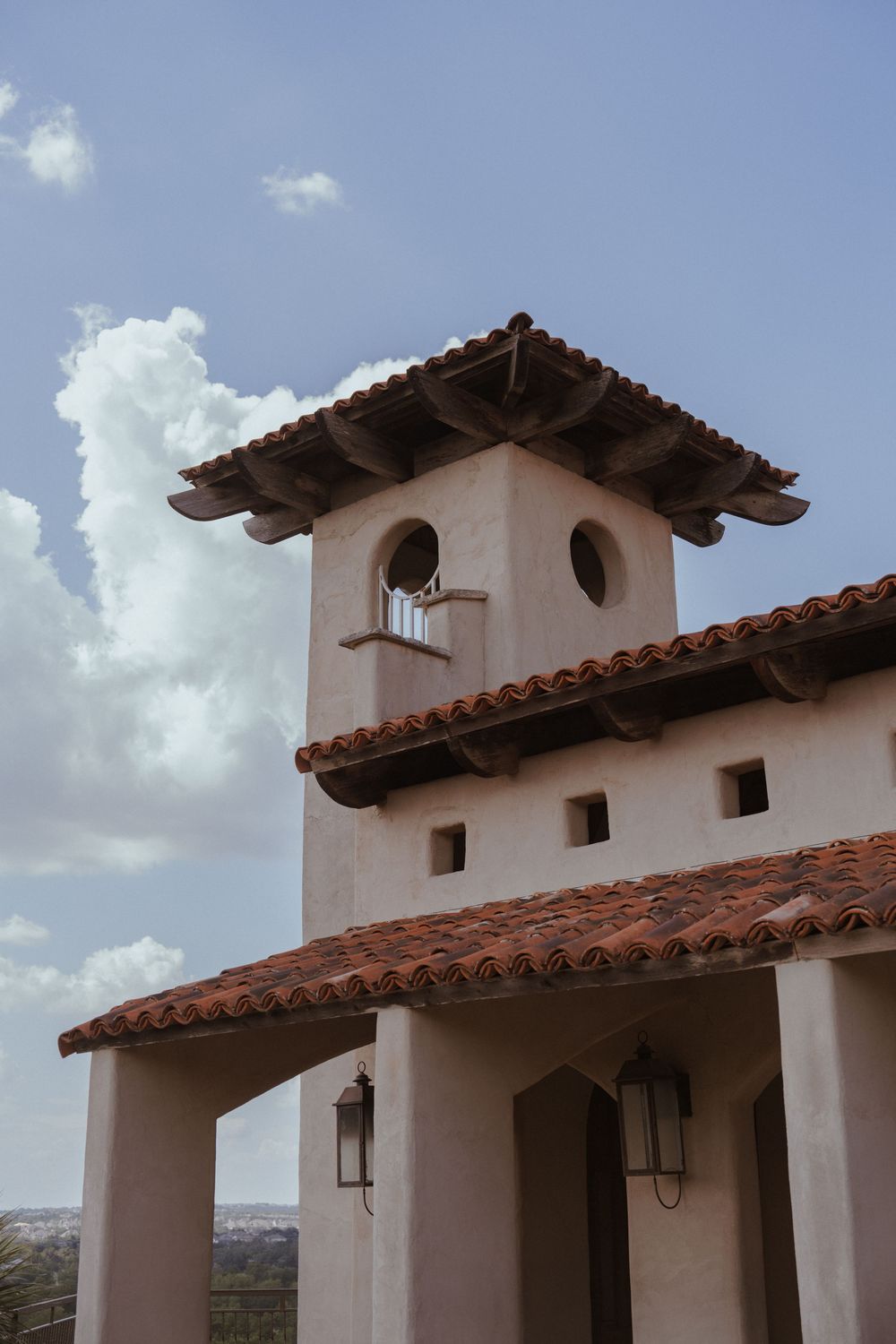 White Spanish colonial building with terra cotta roof tiles and decorative tower details.