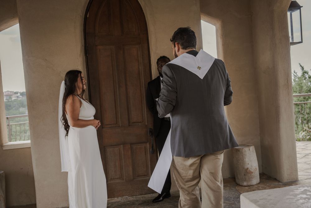 Rustic wooden door frames an entrance in a white stucco wall with hanging lanterns.