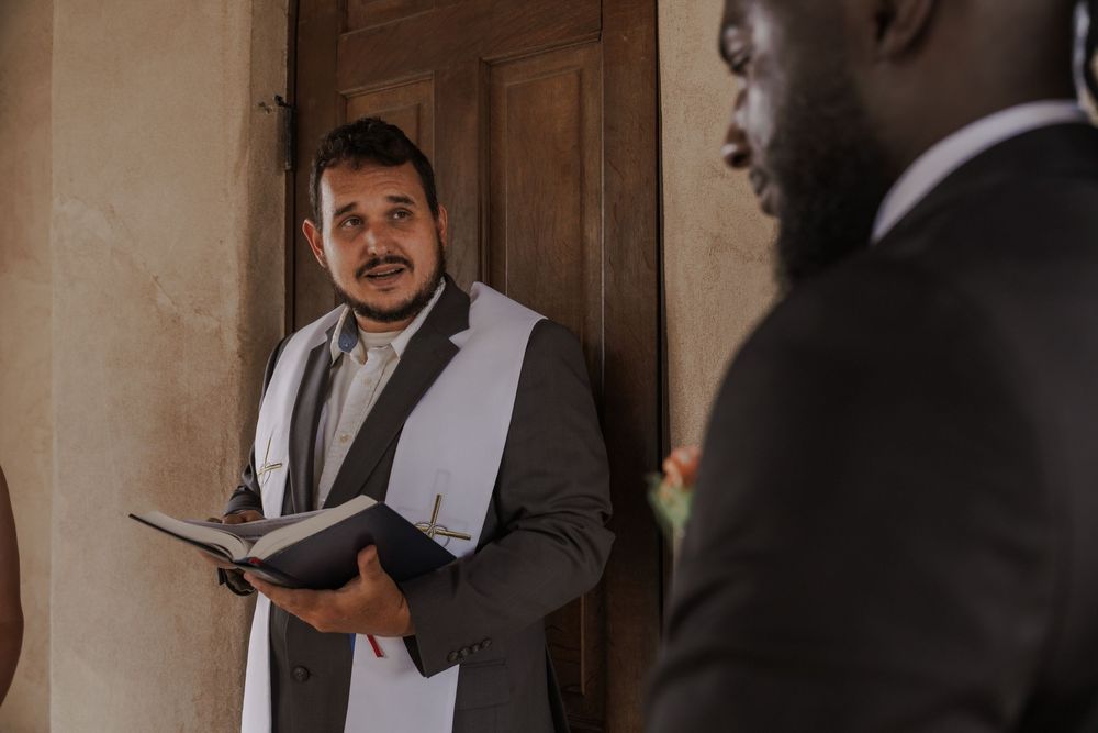 Wedding ceremony preparations inside a rustic chapel with wooden doors and natural lighting.