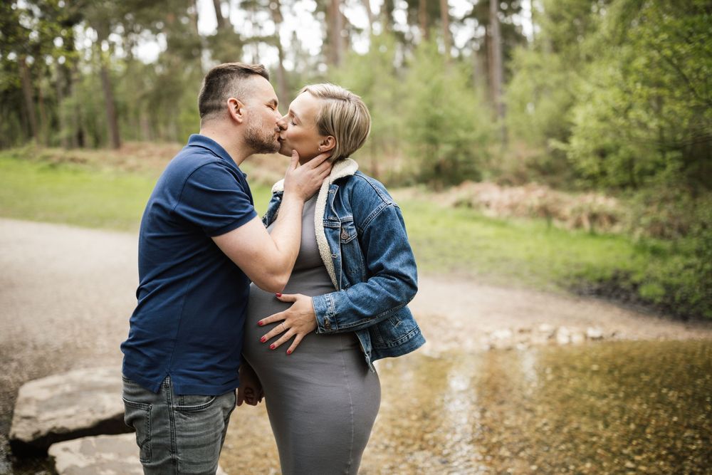 A couple shares an intimate moment together on a wooded path during an outdoor photo session.