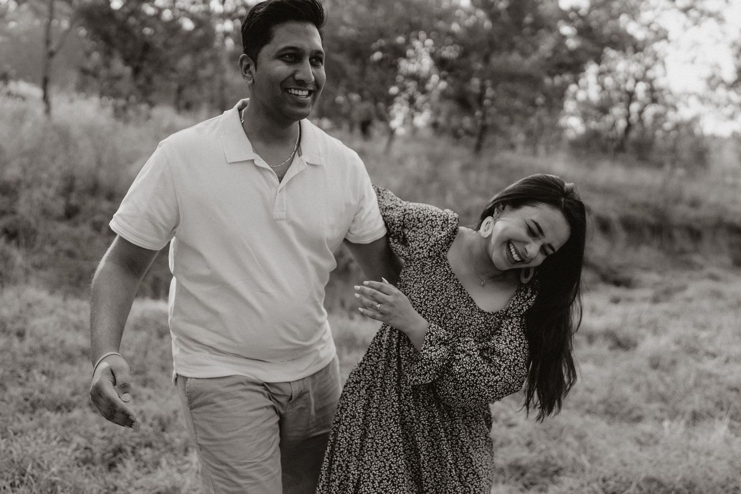 A couple dances together in a field during a photo session.