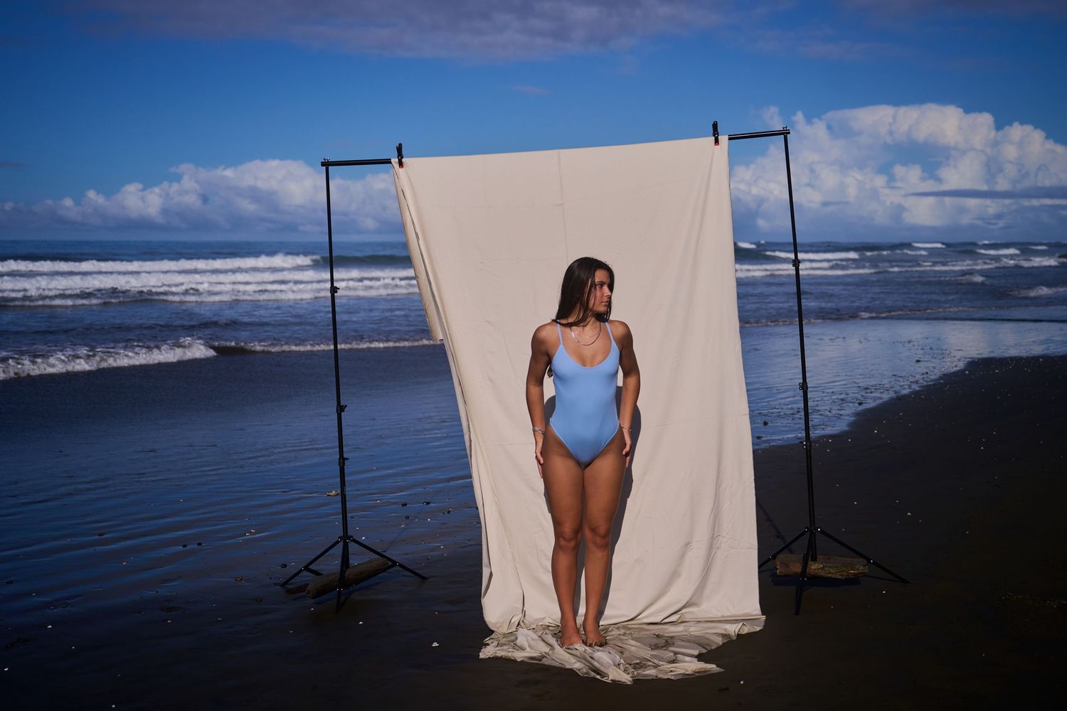 Scenic coastal photography session setup with white backdrop against blue ocean and cloudy sky at beach location.