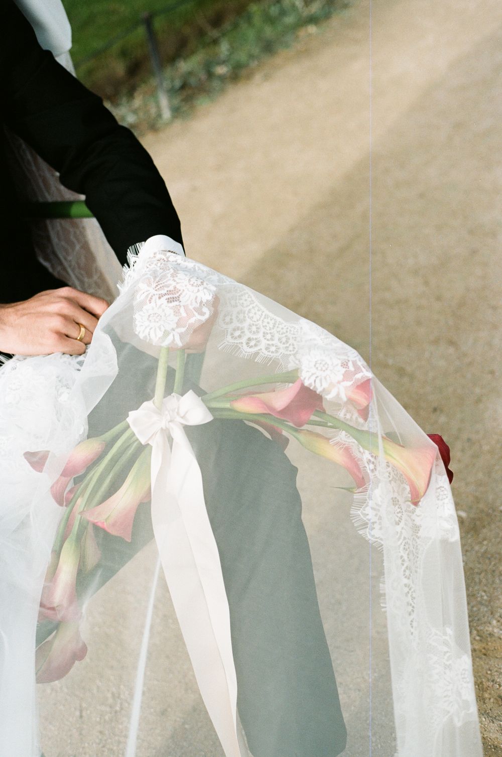 Delicate white lace veil with pink flowers draped elegantly over a wedding dress. Paris film wedding photographer. Fashion wedding