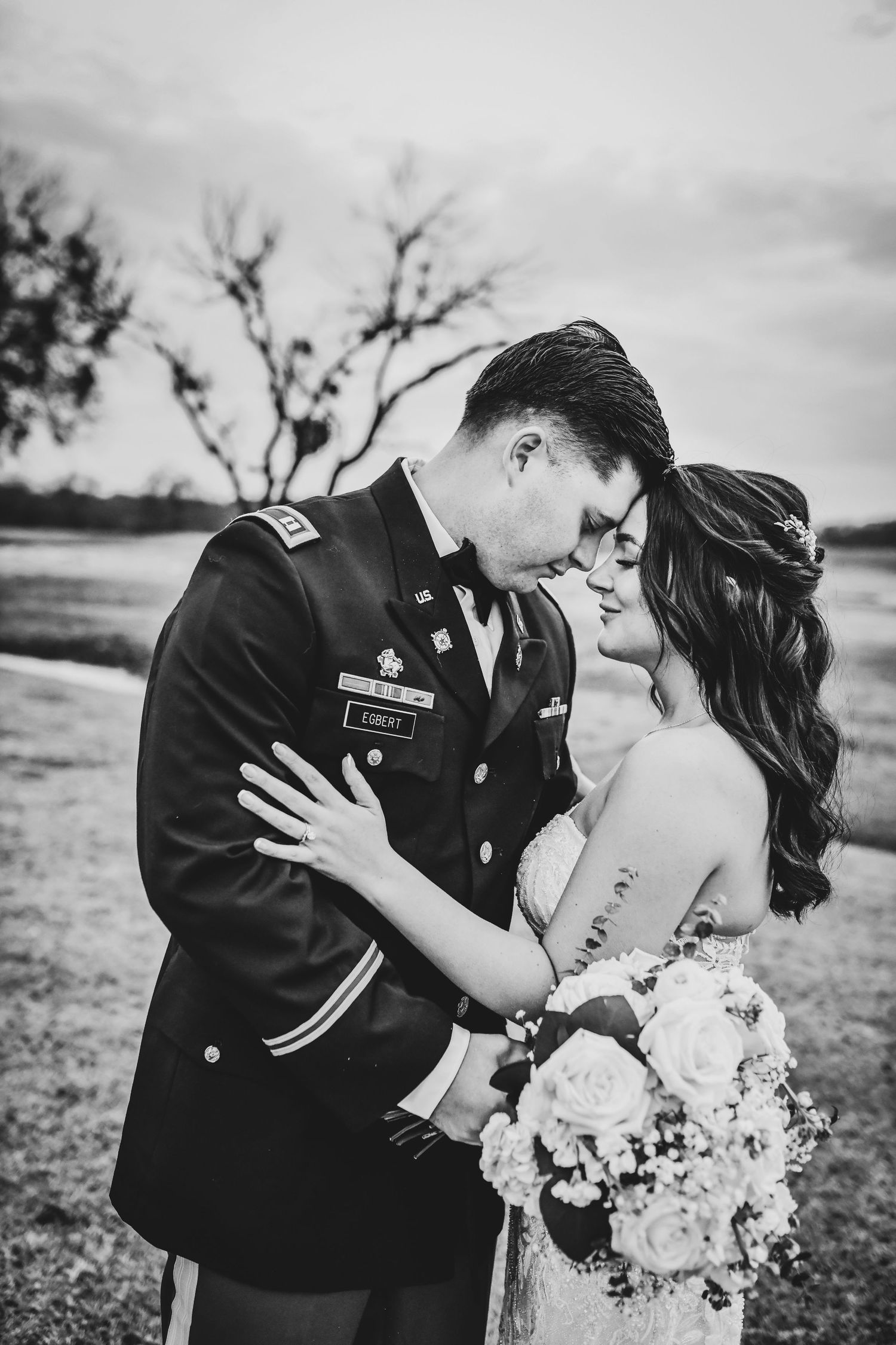 Soft, romantic portrait of couple framed by tall grasses and warm sunset glow.