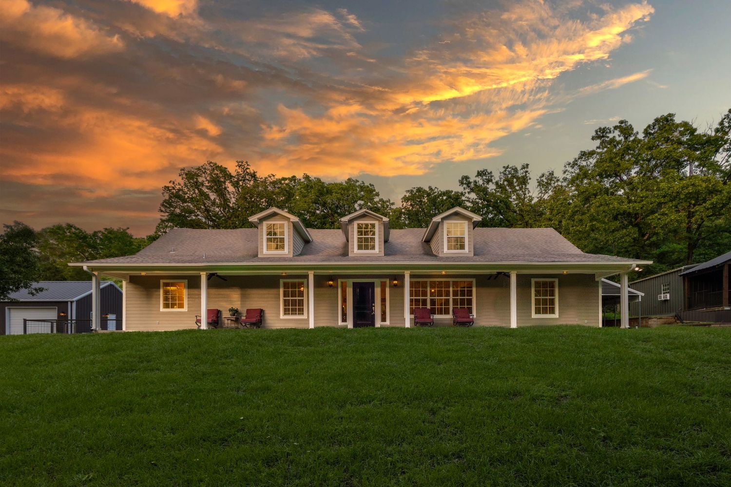 A modern white craftsman style house with a front porch and curved driveway surrounded by green lawn.