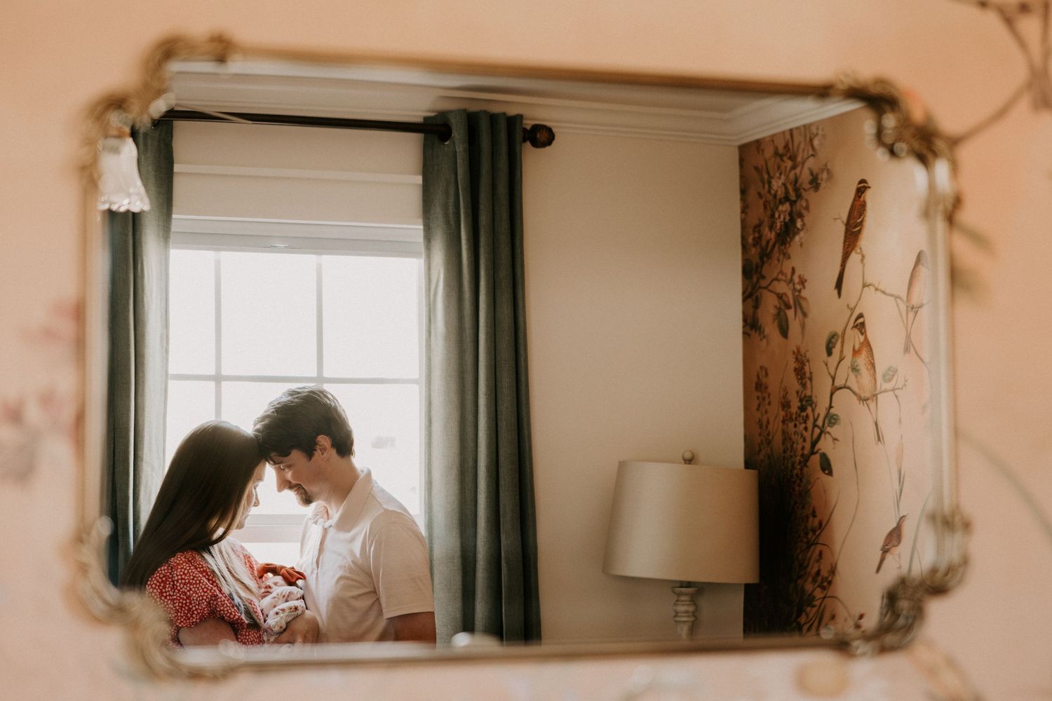 A couple in a cozy living room sits together on a sofa while looking at a laptop screen.