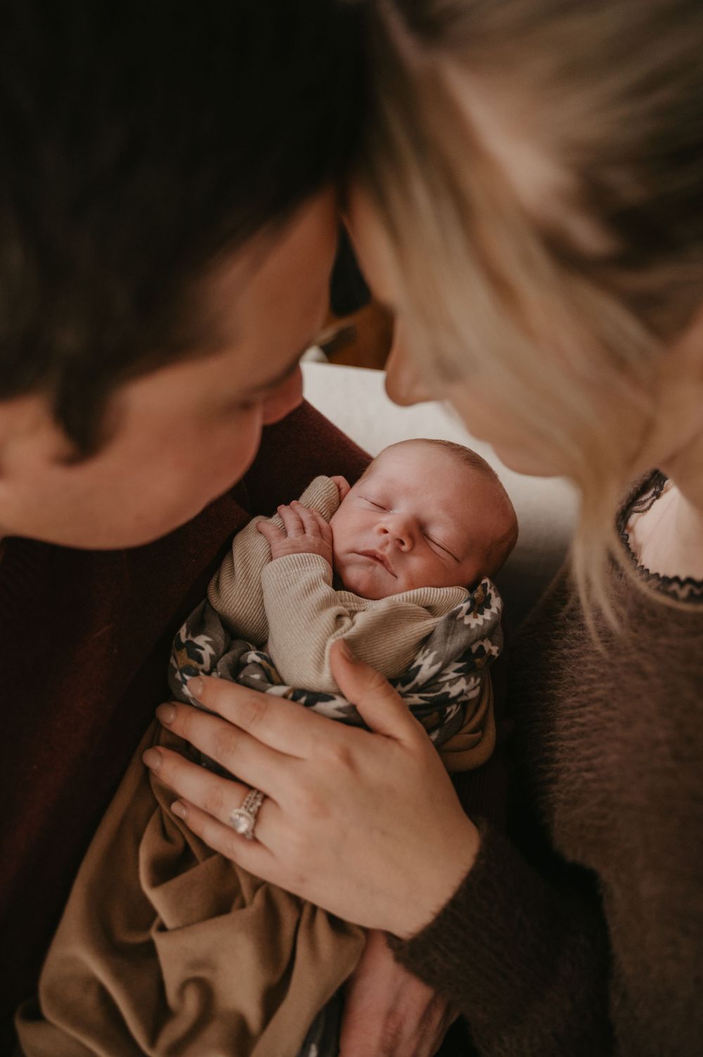 Tender moment between parent and newborn baby in soft natural lighting.