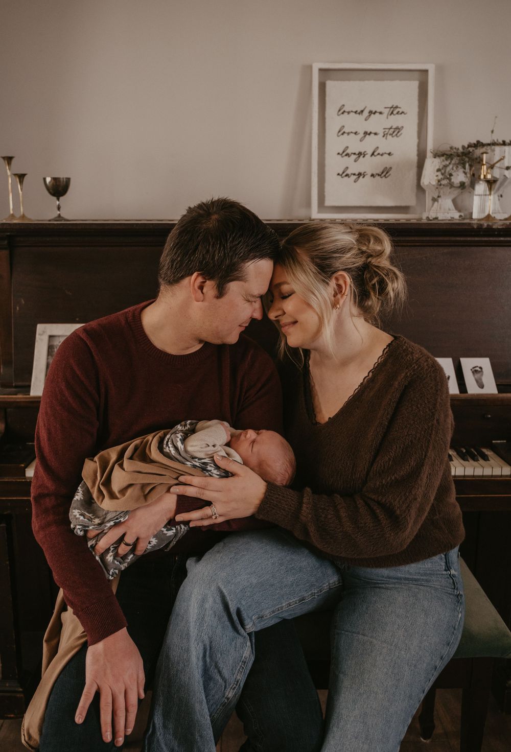 Intimate family moment by piano with newborn baby wrapped in tiger print blanket.