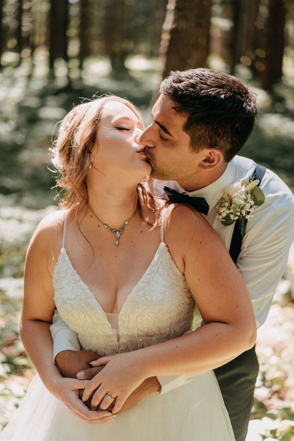 A romantic moment captured between newlyweds in a sunlit forest setting.