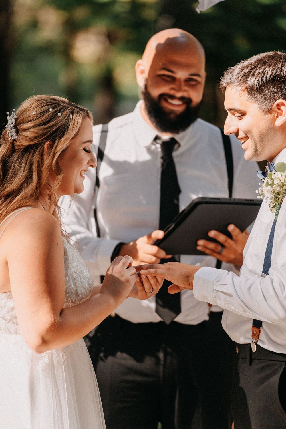 A wedding ceremony moment as rings are exchanged outdoors.