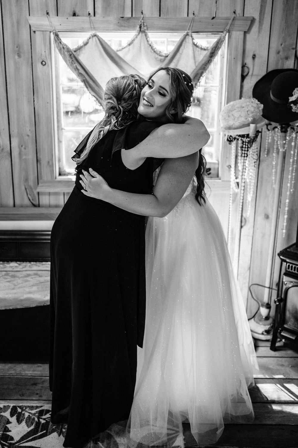Emotional getting ready moment with bridesmaids in black dresses helping with white wedding gown.