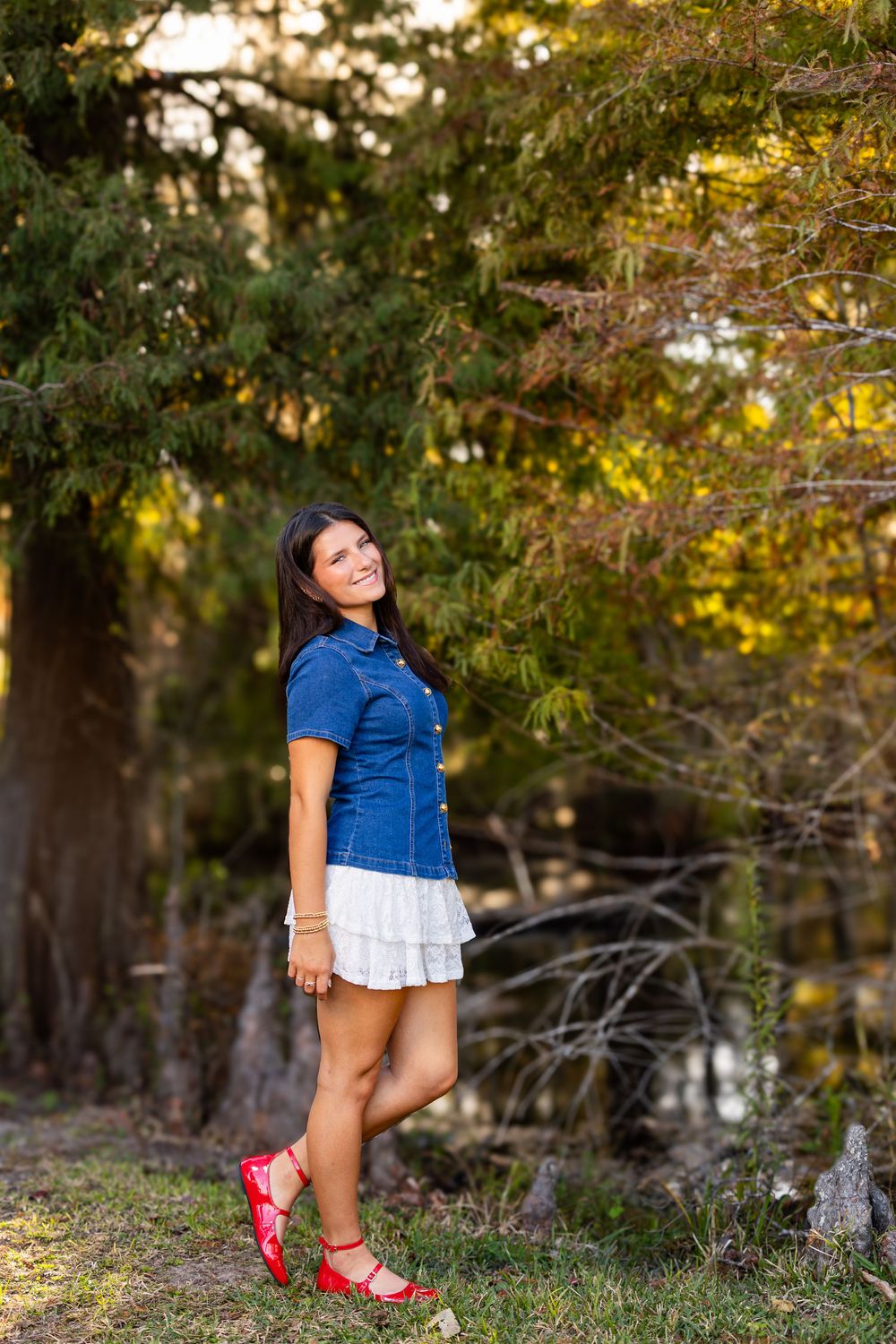 Casual outdoor portrait featuring a denim top and white skirt with red shoes.