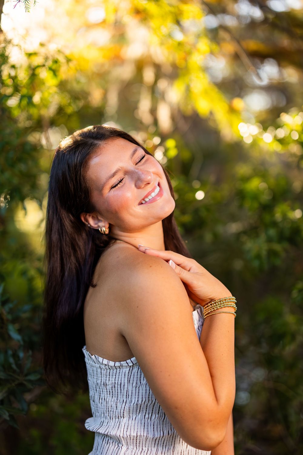 Joyful outdoor portrait with a striped sundress against golden sunset lighting.