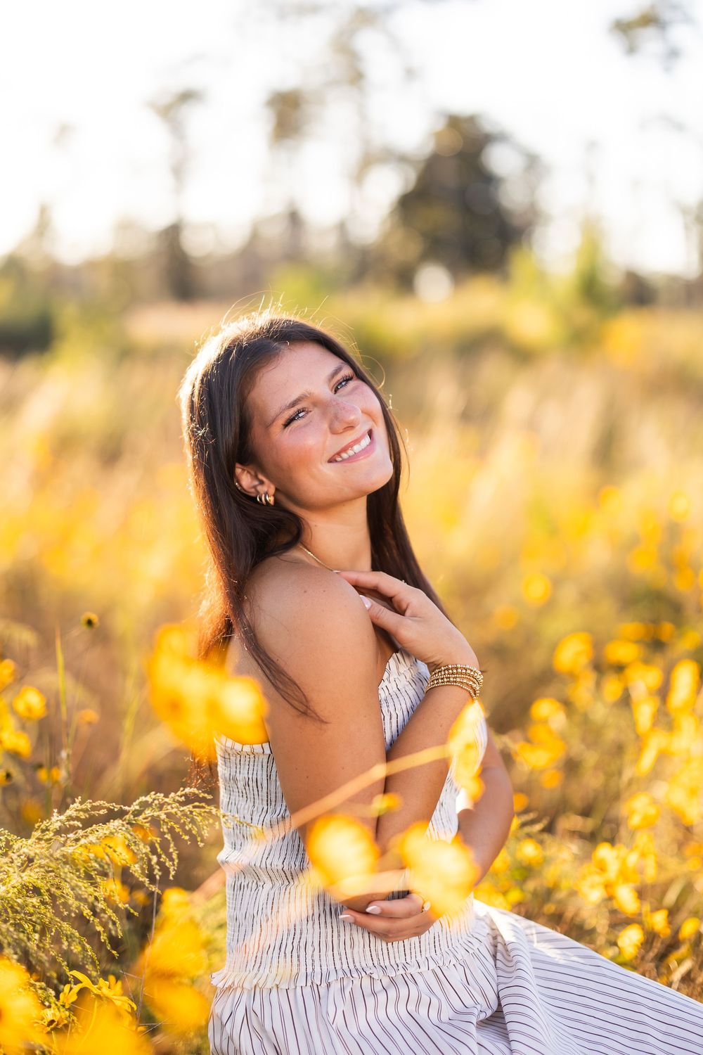 Dreamy portrait in a striped sundress amid golden wildflowers at sunset.