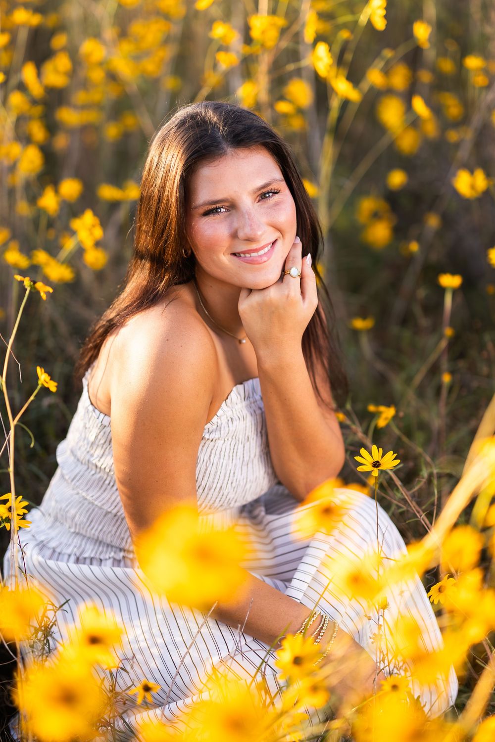 Portrait in a field of vibrant yellow wildflowers during golden hour wearing a striped top.