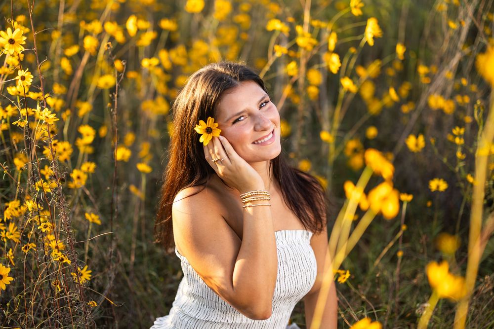 Natural outdoor portrait surrounded by blooming yellow flowers in warm sunlight.