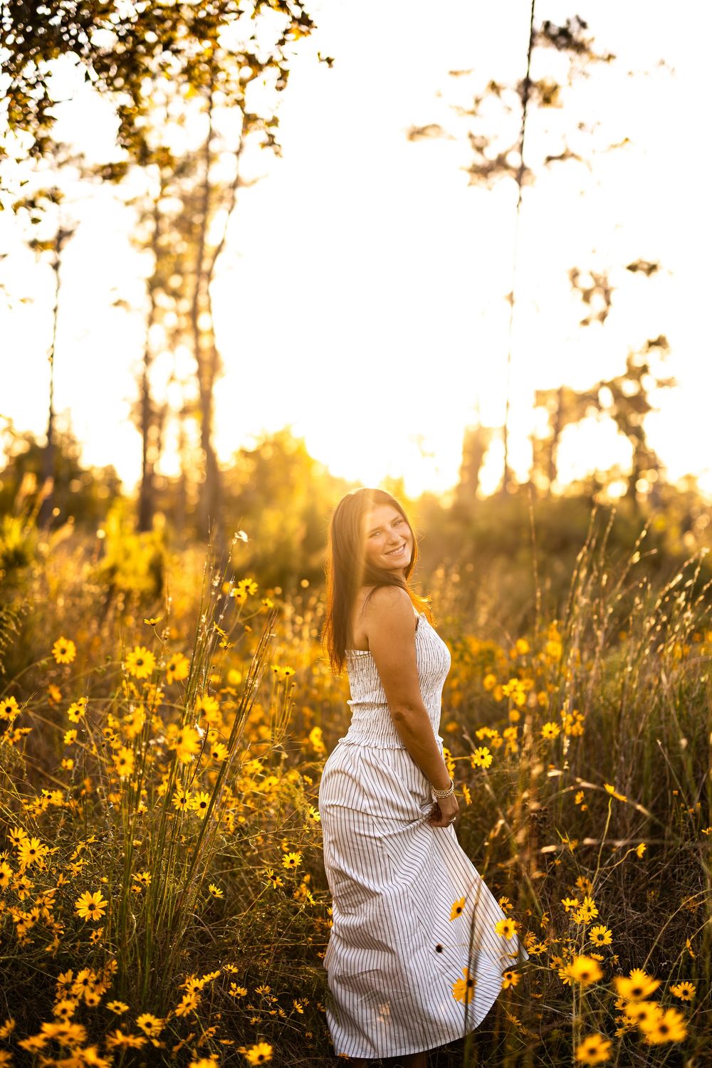Dreamy sunset portrait in a meadow filled with golden wildflowers.
