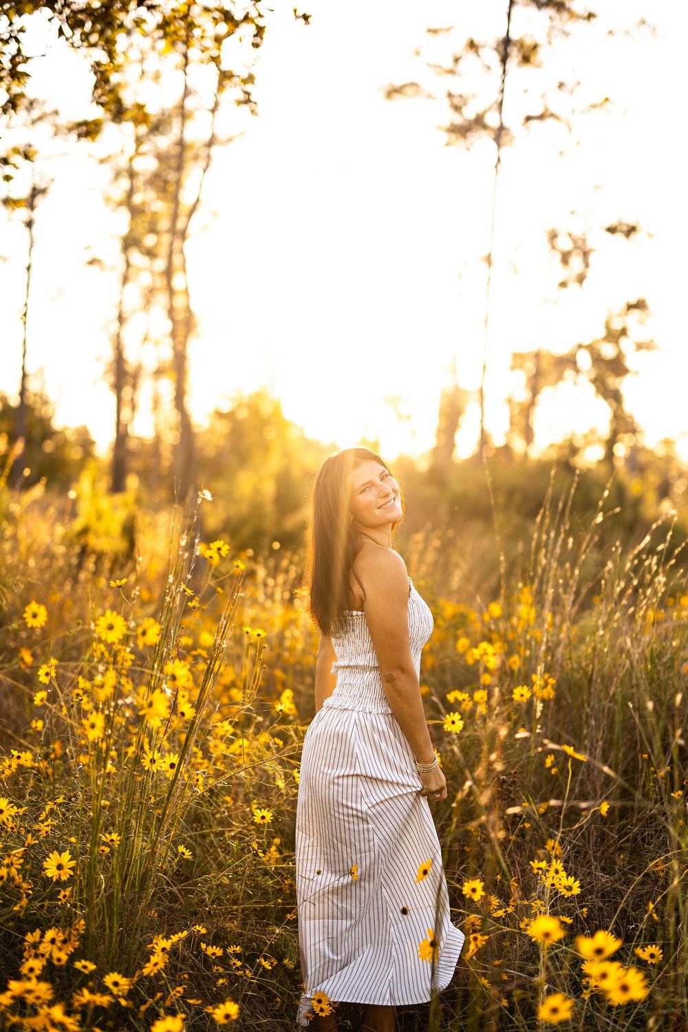 Joyful outdoor photoshoot in a field of yellow flowers during sunset.