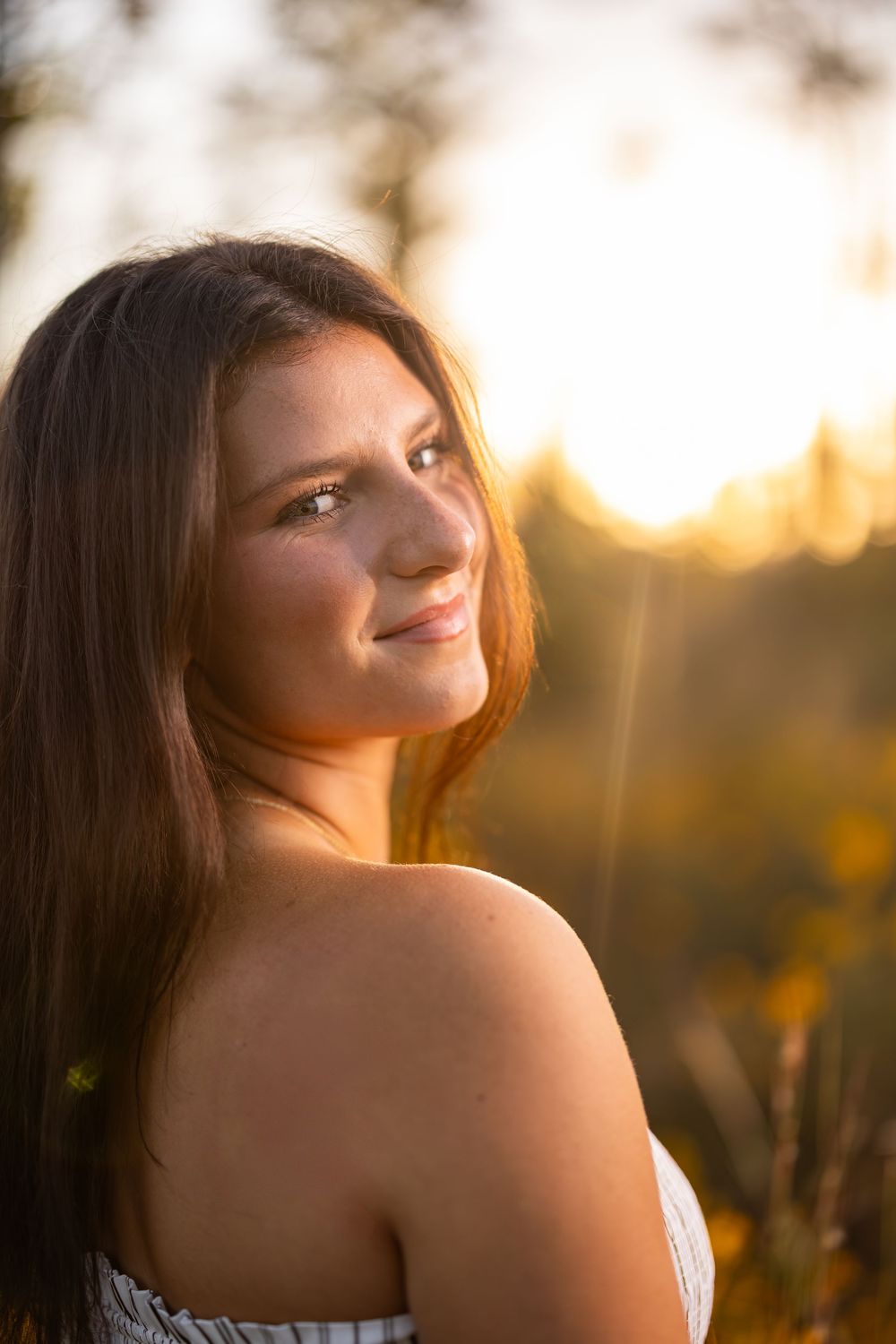 Romantic golden hour portrait with soft backlighting and natural scenery.