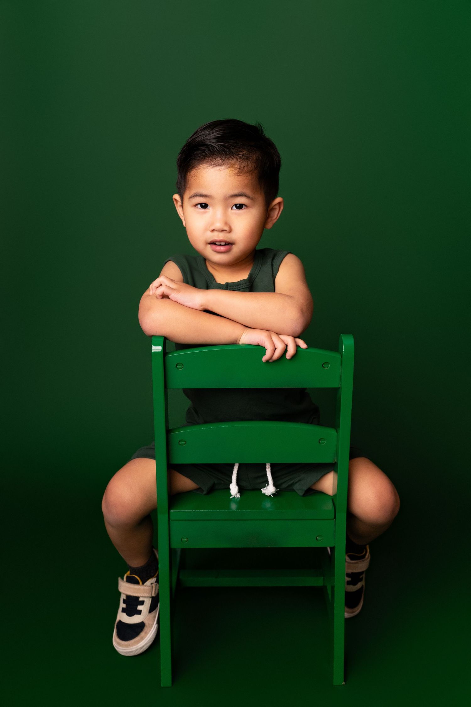 Artistic portraits with a green chair against a dark emerald background.