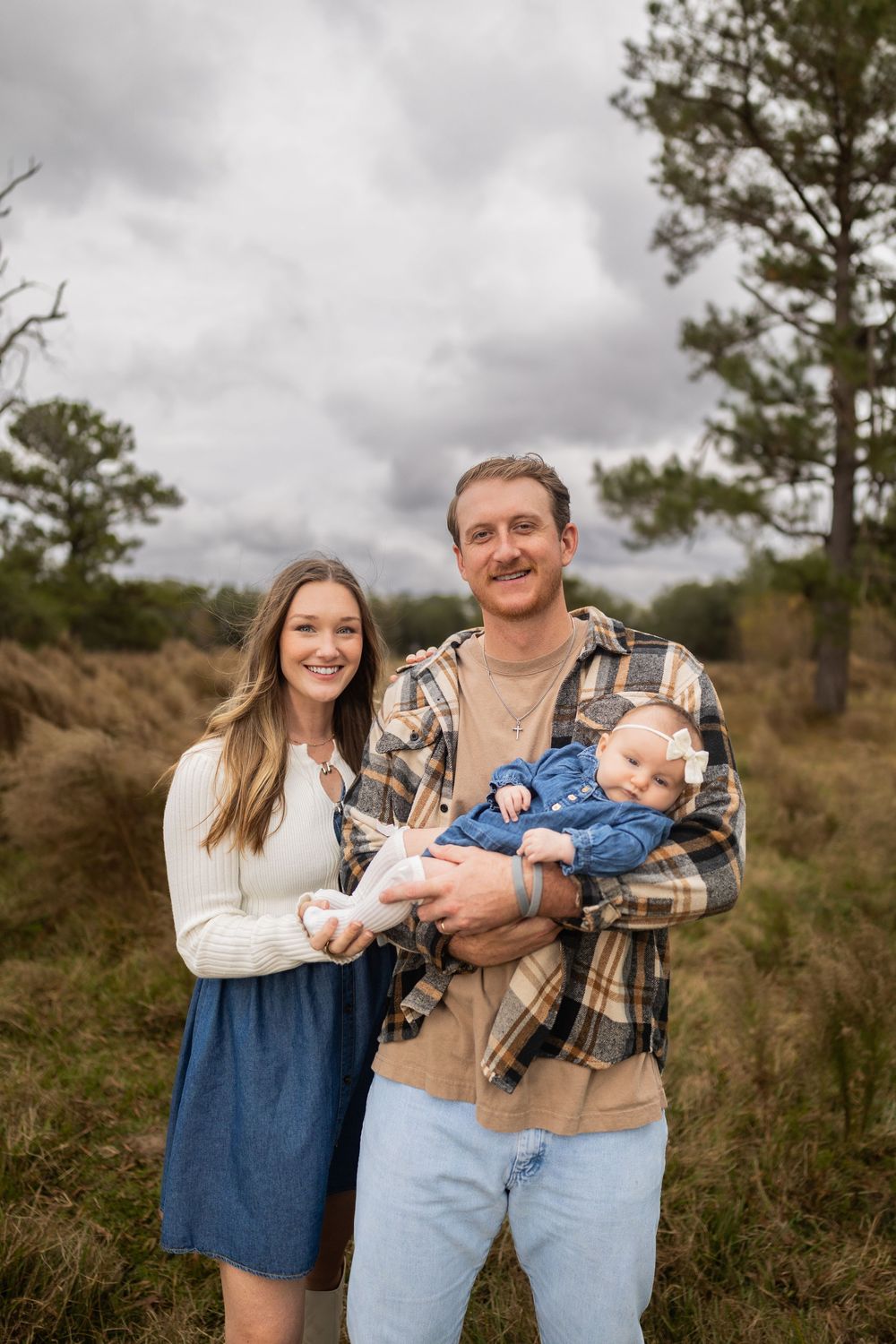 Family portrait in rustic outdoor setting with pine trees.
