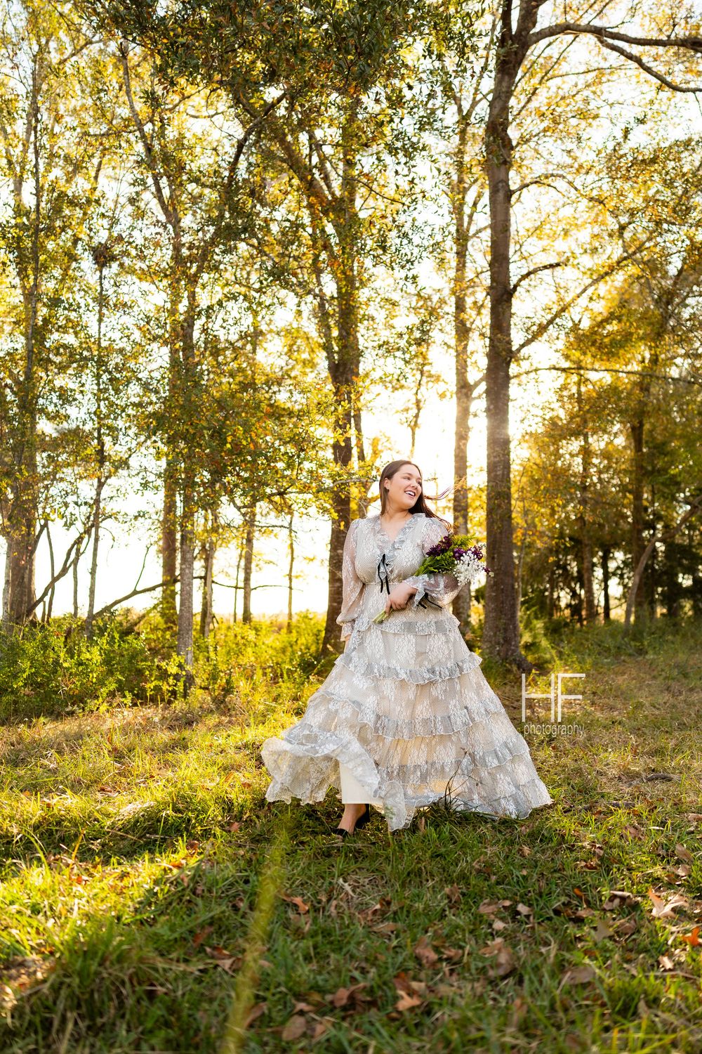 Person in vintage white dress dancing through autumn woods at golden hour.