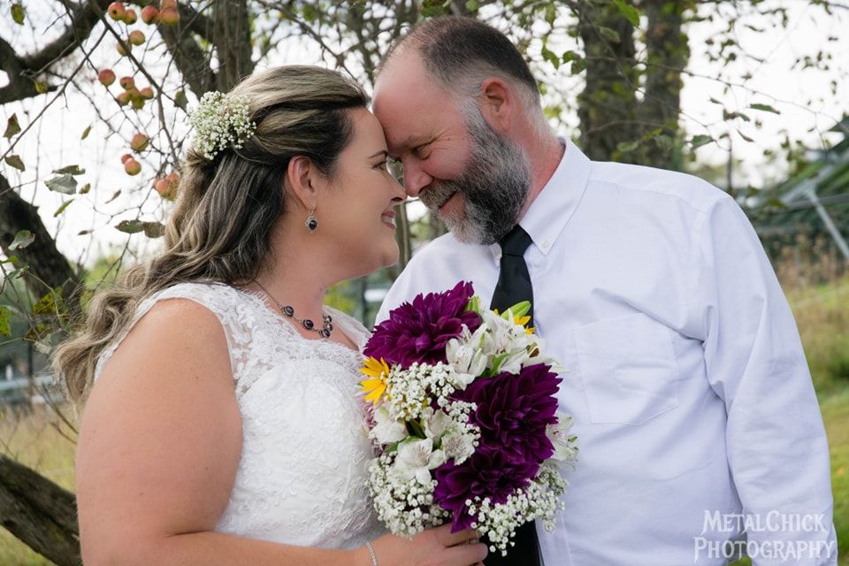 Wedding portrait by Northern Exposure featuring of a husband and wife looking at each other with flowers in the brides hand