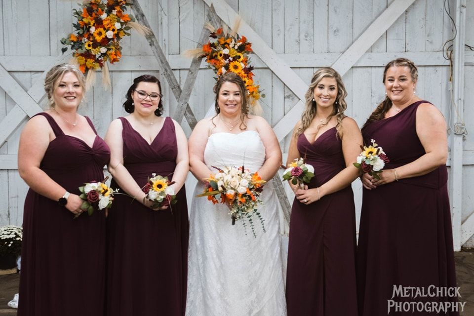Wedding portrait by Northern Exposure featuring the bride and her wedding party in a rustic barn.