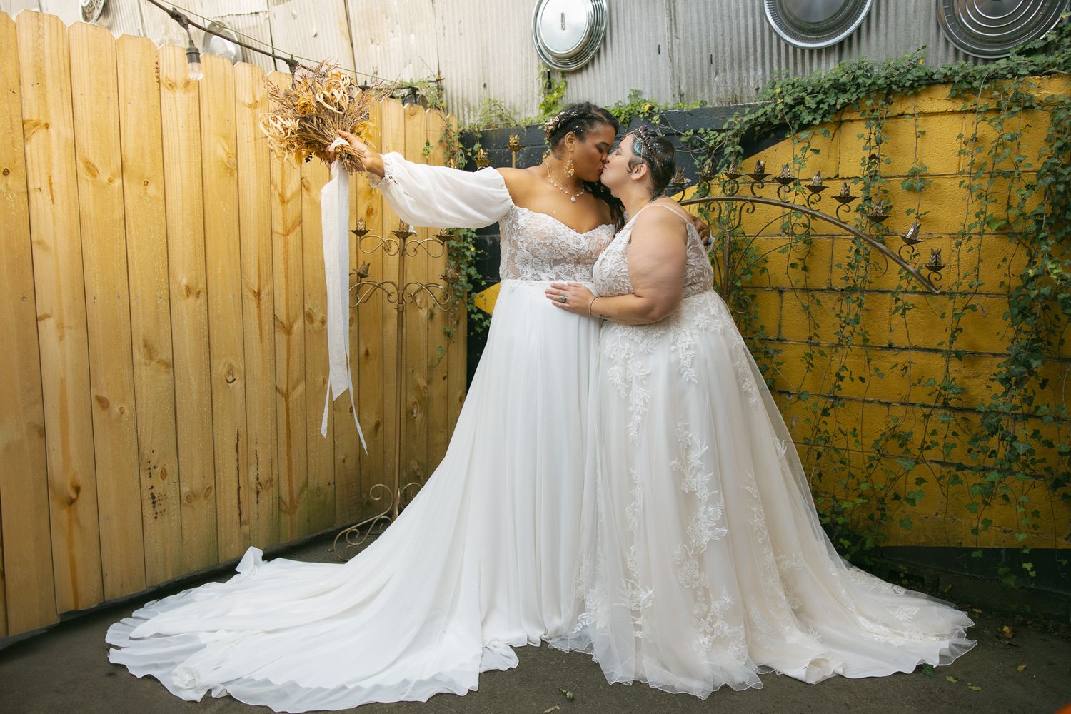 two brides kissing on their wedding day to show wlw pride and sapphic love in their wedding dresses